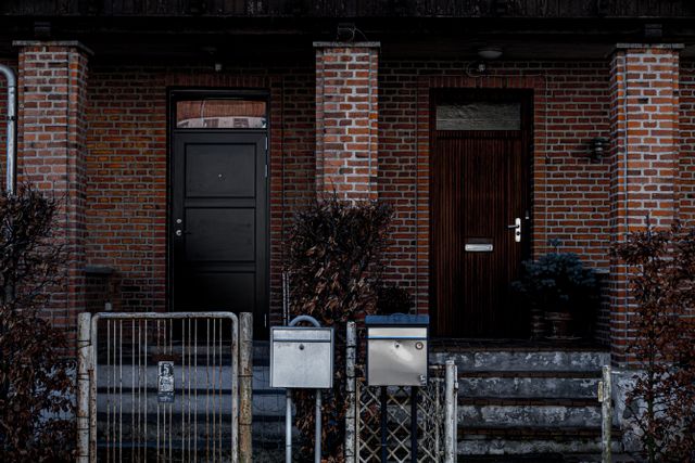 brick building facade with two distinct doorways and metal fencing