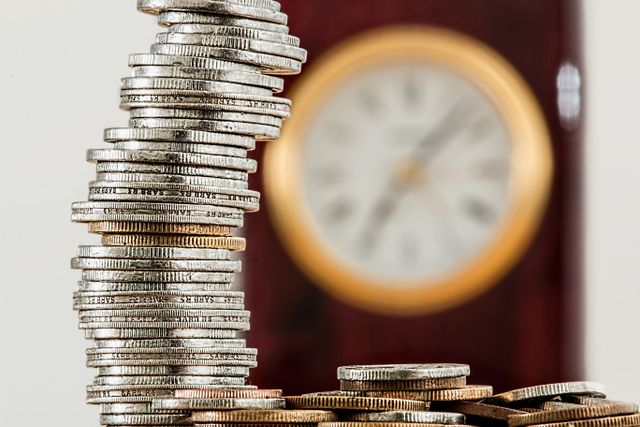 stacked coins with a blurred clock